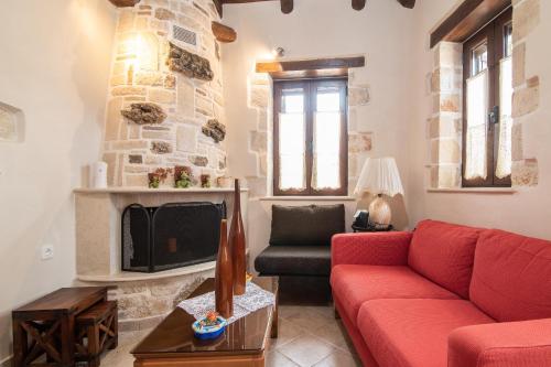 een woonkamer met een rode bank en een open haard bij Eva Traditional Houses in Volimes in Áno Volímai