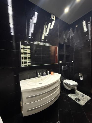 a black bathroom with a sink and a toilet at Квартира в центре Тбилиси in Tbilisi City