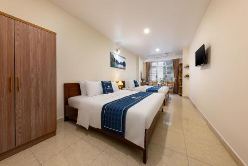 a bedroom with two beds and a tv on a wall at Mountain Pearl Hotel in Cat Ba