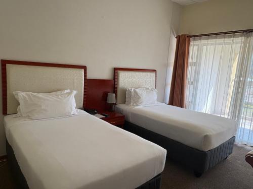 a hotel room with two beds and a window at Ave maria hotel and conferencing in Gaborone