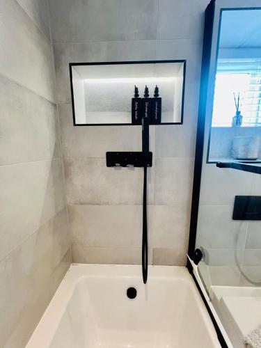 a bath tub in a bathroom with a sink at Poppies in Colchester