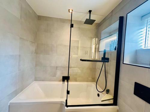 a bathroom with a bath tub with a shower at Poppies in Colchester