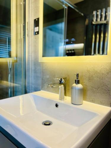 a bathroom sink with a soap dispenser on it at Poppies in Colchester