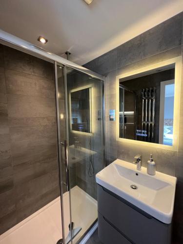 a bathroom with a white sink and a shower at Poppies in Colchester
