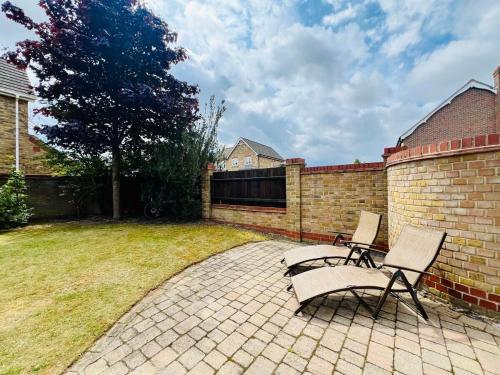 a patio with two chairs and a brick wall at Poppies in Colchester