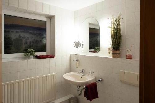 a white bathroom with a sink and a mirror at Schnuckenstube Souterrain im Grünen in Schneverdingen