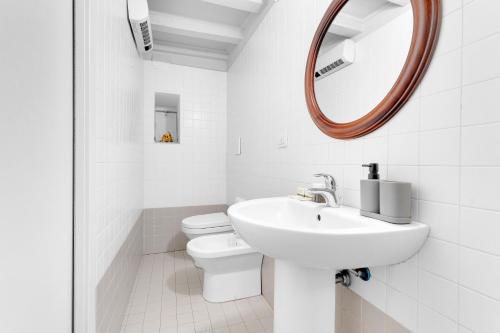 a white bathroom with a sink and a mirror at The house of Ripa di porta ticinese 13 in Milan