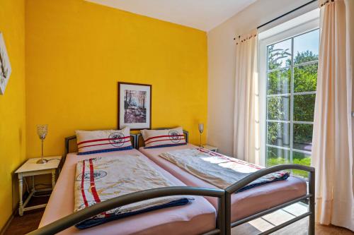 a bedroom with a bed and a yellow wall at Gästehaus Ziegler in Neuenkirchen