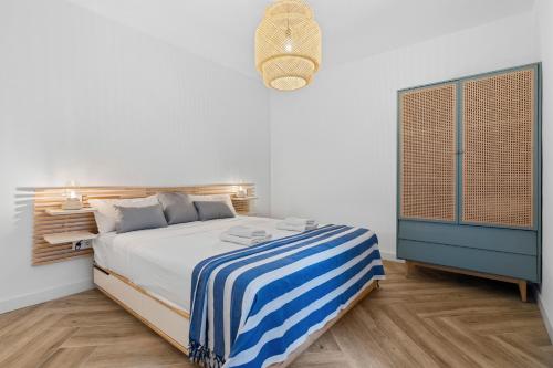 a bedroom with a bed with a blue and white striped blanket at Casa Rija - Renovated 2BR - Heart of Mijas Pueblo in Mijas
