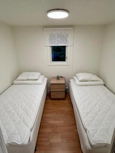 Dos camas en una habitación pequeña con ventana. en Mysig skogsstuga mitt i naturen, en Våxtorp