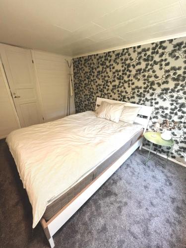 Un dormitorio con una cama y una pared con flores. en Mysig skogsstuga mitt i naturen, en Våxtorp
