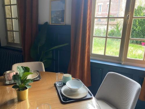 a dining room table with plates and dishes on it at Appartement confortable aux Andelys - 90 m² avec parking in Les Andelys