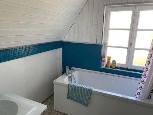 a bathroom with a tub and a sink and a window at Grande maison à Santes avec jardin in Santes