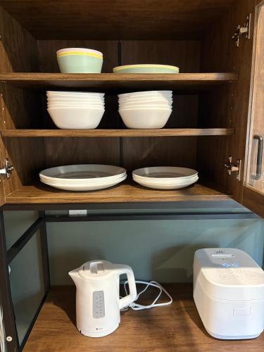 a cabinet with plates and bowls and a toaster at TOKYO STAY in Kamata in Tokyo