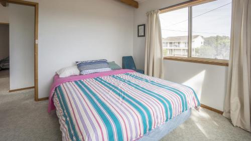 a bedroom with a bed and a large window at Summer House On Kurrawa - stunning beach views in Kioloa