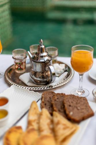 a table with a tea kettle and bread and glasses of orange juice at Riad Kasbah privilège and SPA in Marrakech