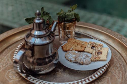 a plate with cookies and a tea kettle on a table at Riad Kasbah privilège and SPA in Marrakech