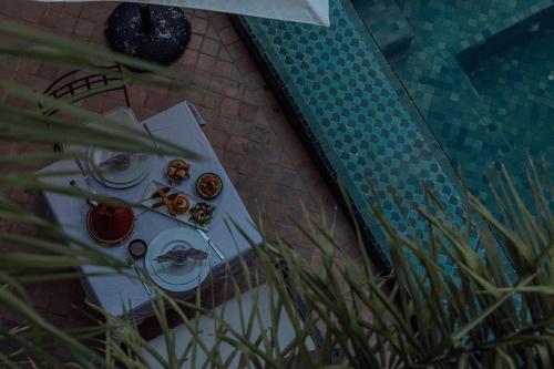 a table next to a swimming pool with food on it at Riad Kasbah privilège and SPA in Marrakech