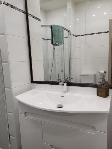 a white bathroom with a sink and a mirror at Siauliai Apartments - Traku in Šiauliai