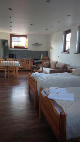 a room with three beds and a living room with a couch at Agroturystyka Dzika Łąka apartament in Słonów