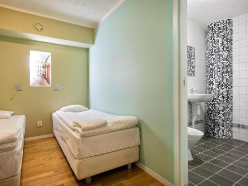 a bathroom with a bed and a sink and a toilet at Mosebacke Hostel in Stockholm