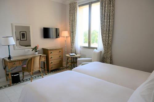 a hotel room with two beds and a desk and a window at The Phoenicia Malta - The Leading Hotels of the World in Valletta
