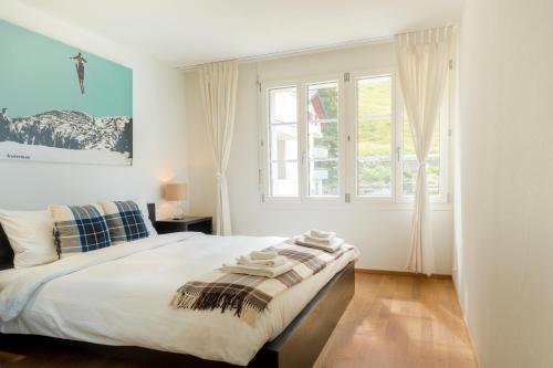 a white bedroom with a bed and a window at Holzgasse Apartment in Andermatt