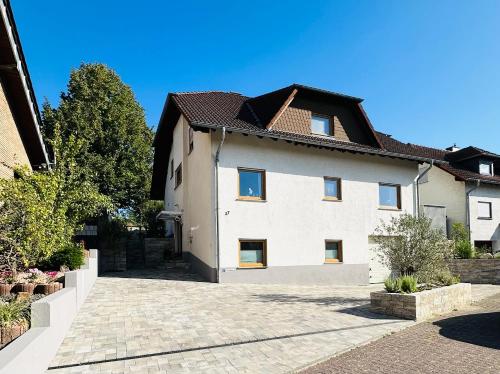 ein großes weißes Haus mit einer Ziegelsteinfahrt in der Unterkunft Nähe Mainz - Ferienwohnung - Apartment Breivogel in Wörrstadt in Wörrstadt