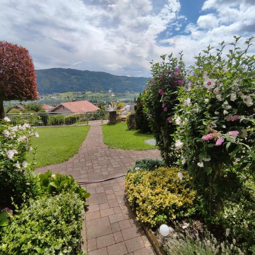 a garden with flowers and a brick walkway at Haus Maria Bodensdorf in Tratten