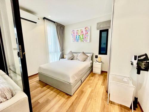 una camera da letto bianca con un letto e uno specchio di Title HALO 1 - Modern 1BR Pool View Walk to Nai Yang Beach a Nai Yang Beach