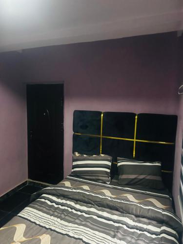 a bedroom with a bed with a black headboard and pillows at Revelation hotel in Okunaja