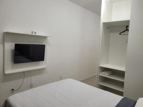 a bedroom with a bed and a tv on a wall at Flat Completo in Cotia