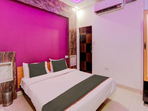 a bedroom with a large bed with a purple wall at Super Collection O Kiara Guest House in Lucknow
