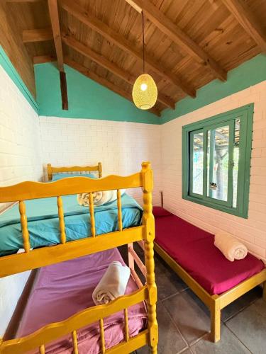 a bedroom with two bunk beds and a window at Hostel Pantera do Rosa in Praia do Rosa