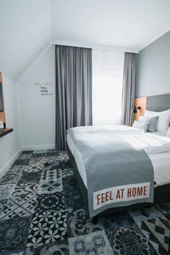 a bedroom with a bed with a feel at home sign on it at das seidl - Hotel & Tagung - München West in Puchheim