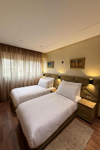 two beds in a hotel room with white pillows at Appart Hôtel Oleandro in Casablanca