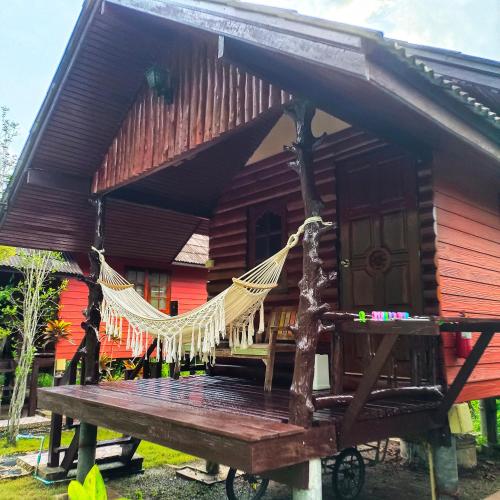 a hammock in front of a wooden house at TA YAI HOMESTAY (ตา ยาย โฮมสเตย์) in Ko Kood