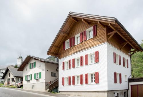 a white building with red shutters on a street at HOSPENTAL Chalet in Arni Alp