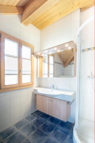 a bathroom with a sink and a mirror and a tub at HOSPENTAL Chalet in Arni Alp