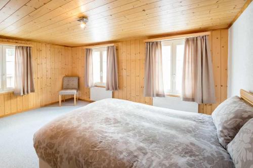 a bedroom with a large bed in a room with windows at HOSPENTAL Chalet in Arni Alp