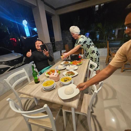 a group of people sitting around a table with food at Ridho Malik Hotel in Bumbang