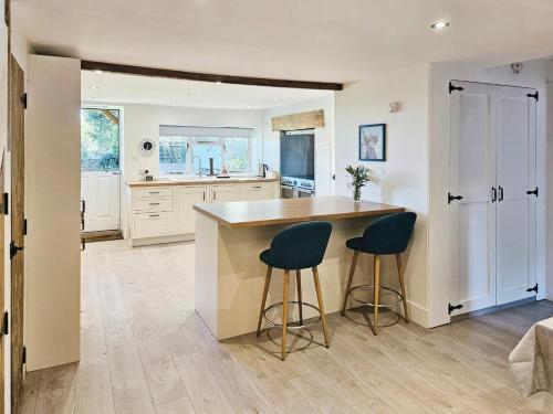 a kitchen with a counter and two stools in it at The Farmhouse in Meysey Hampton
