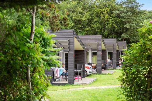 a row of cottages with people sitting on the porch at First Camp Skovlund Camping & Cottages in Båring