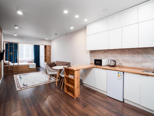 a kitchen with white cabinets and a table and chairs at Апартамент на Тулебаева! in Zhezdi