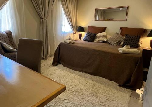 1 dormitorio con 1 cama grande, mesa y silla en The Lion Room at Frederick's Place, en Pretoria