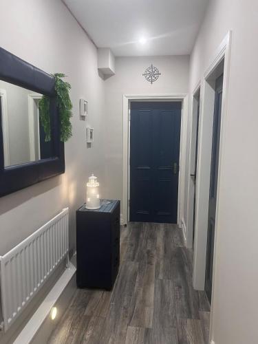 a hallway with a black door and a table with a candle at The C Den Amazing Seaview, ground floor, free wifi & parking in Whitehead