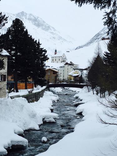 a river with snow and buildings and a mountain at RIVER Apartment in Arni Alp