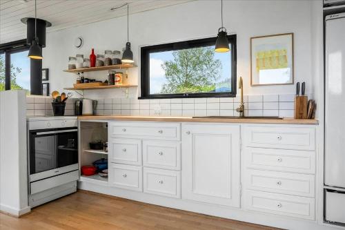 a kitchen with white cabinets and a window at Summer House Close To Nature By The Limfjord in Nykøbing Mors