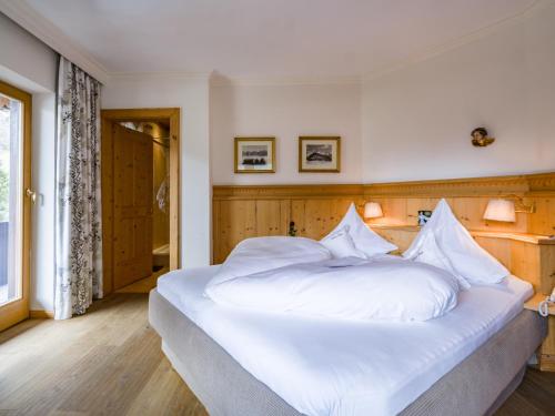 a large white bed with white sheets and pillows at Relais&Châteaux Spa-Hotel Jagdhof in Neustift im Stubaital