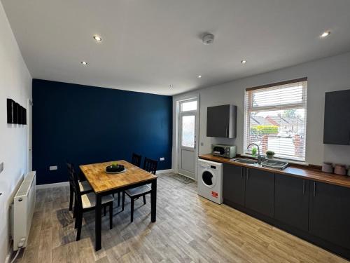 a kitchen with a table and a blue wall at Cosy Escape Near Nature & Town 